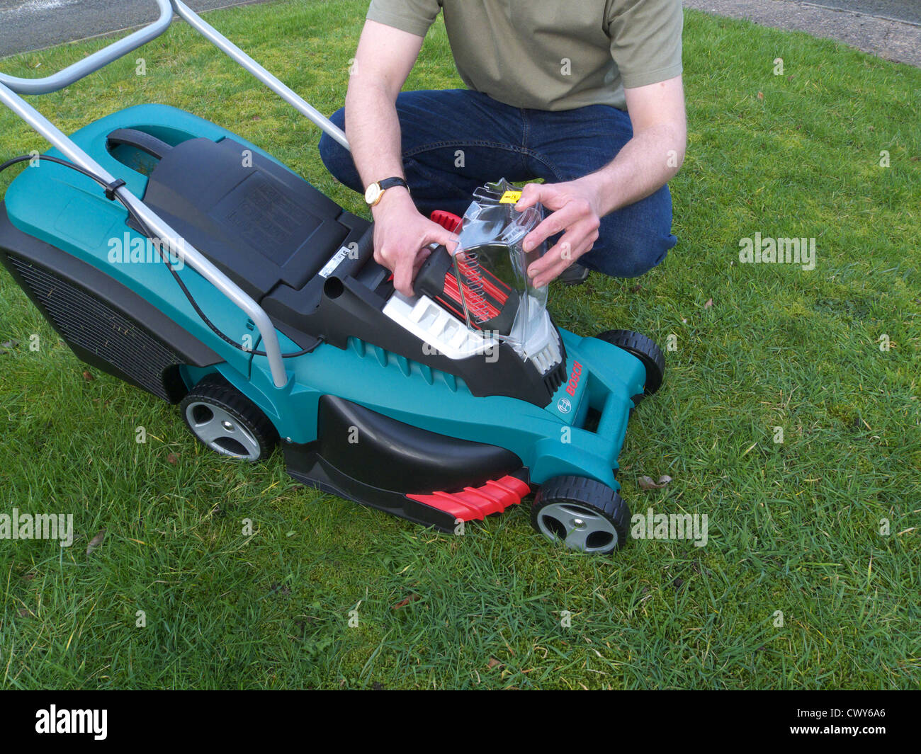 Caucasian Man Changing a Rechargeable Battery on a Bosch Rotak Rechargeable Lawnmower MODEL RELEASED Stock Photo