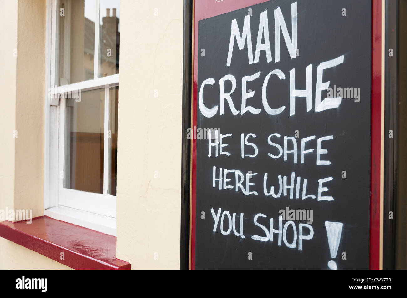 Funny pub sign offering Man Creche for women wanting to shop. Stock Photo