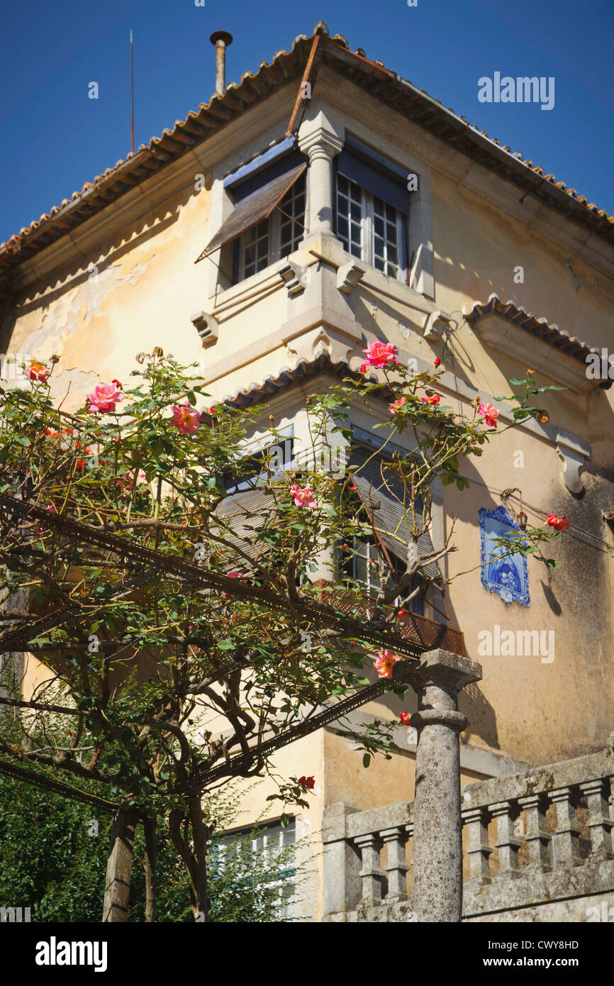 Traditional Portuguese architecture of an interesting house in Viseu with pink climbing roses over a pergola Stock Photo