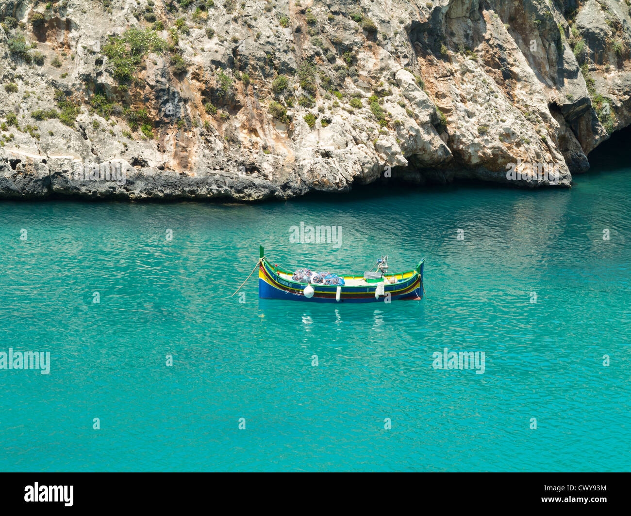 Coastal scene of clear blue water and fishing boat, Island of Gozo, Mediterranean Sea Stock Photo