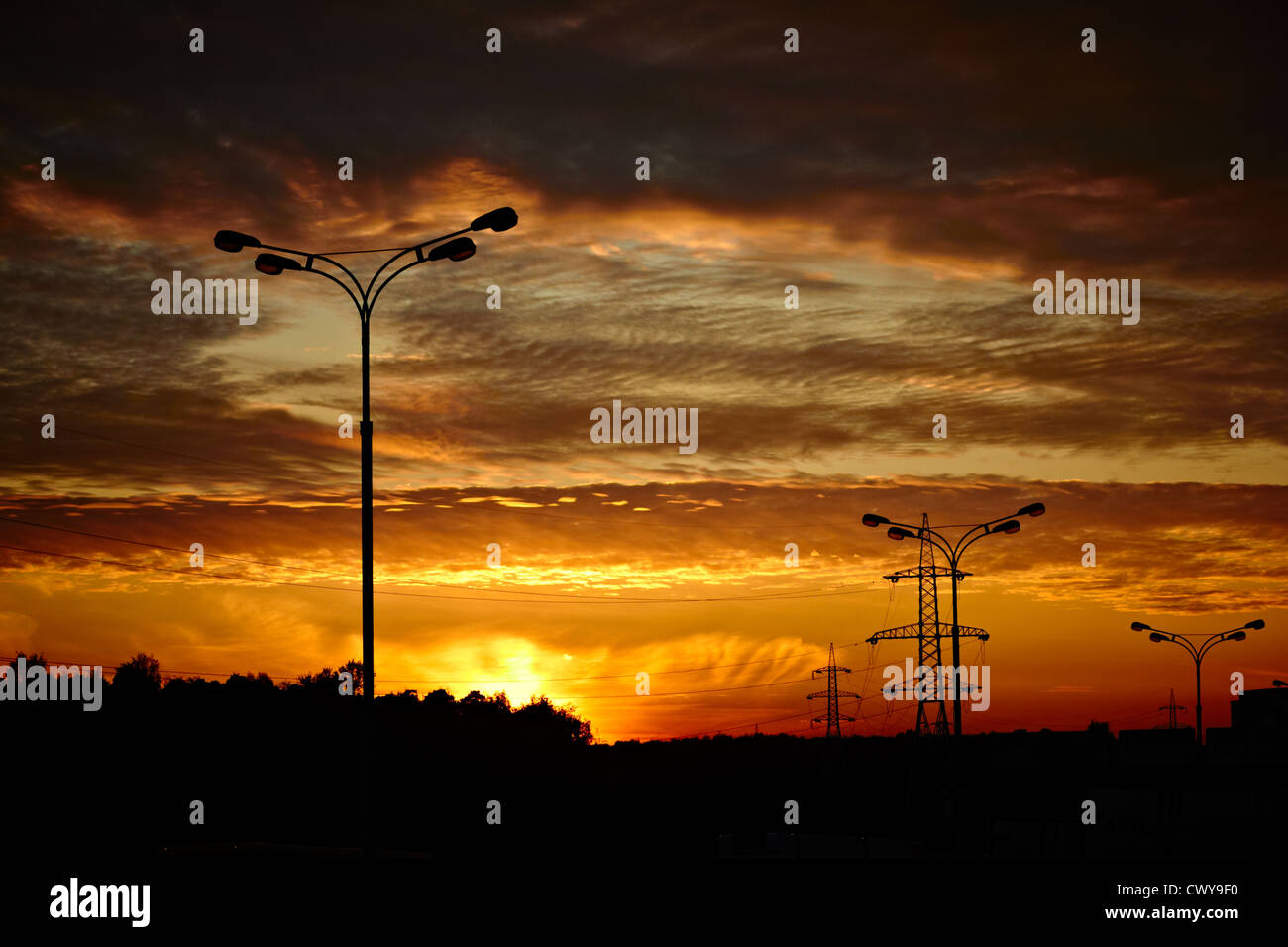 Powerlines and a road lantern at sunset. Stock Photo