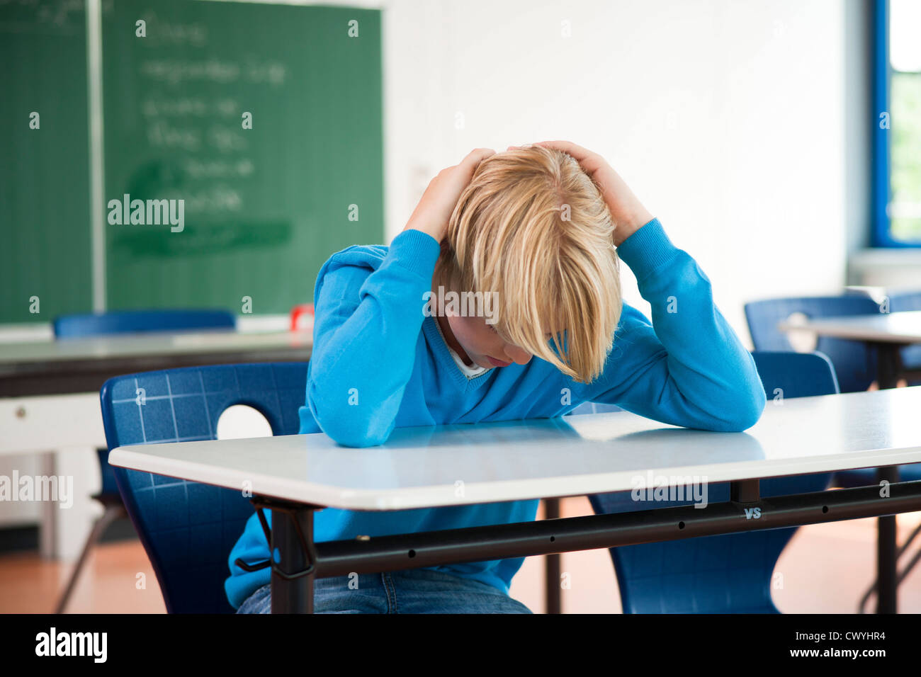 Exhausted schoolboy in classroom Stock Photo
