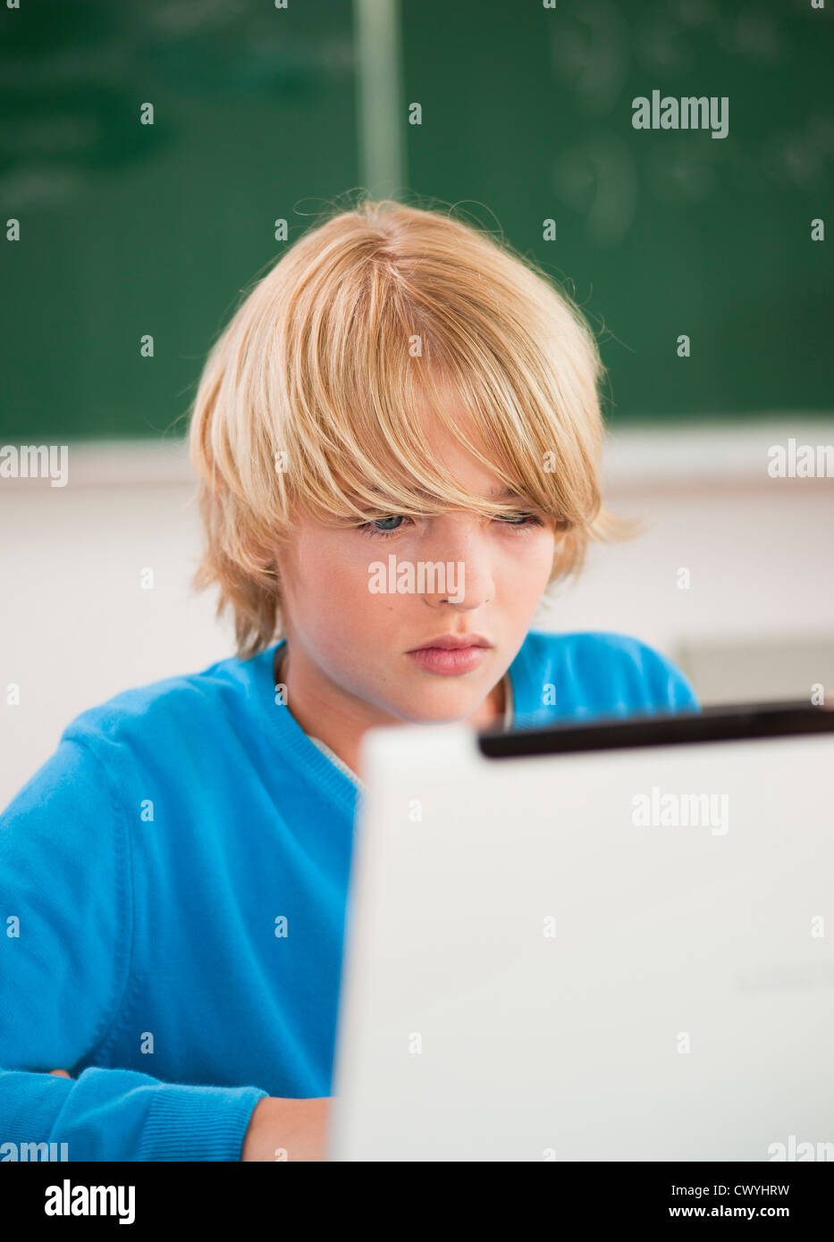 Schoolboy using laptop in classroom Stock Photo