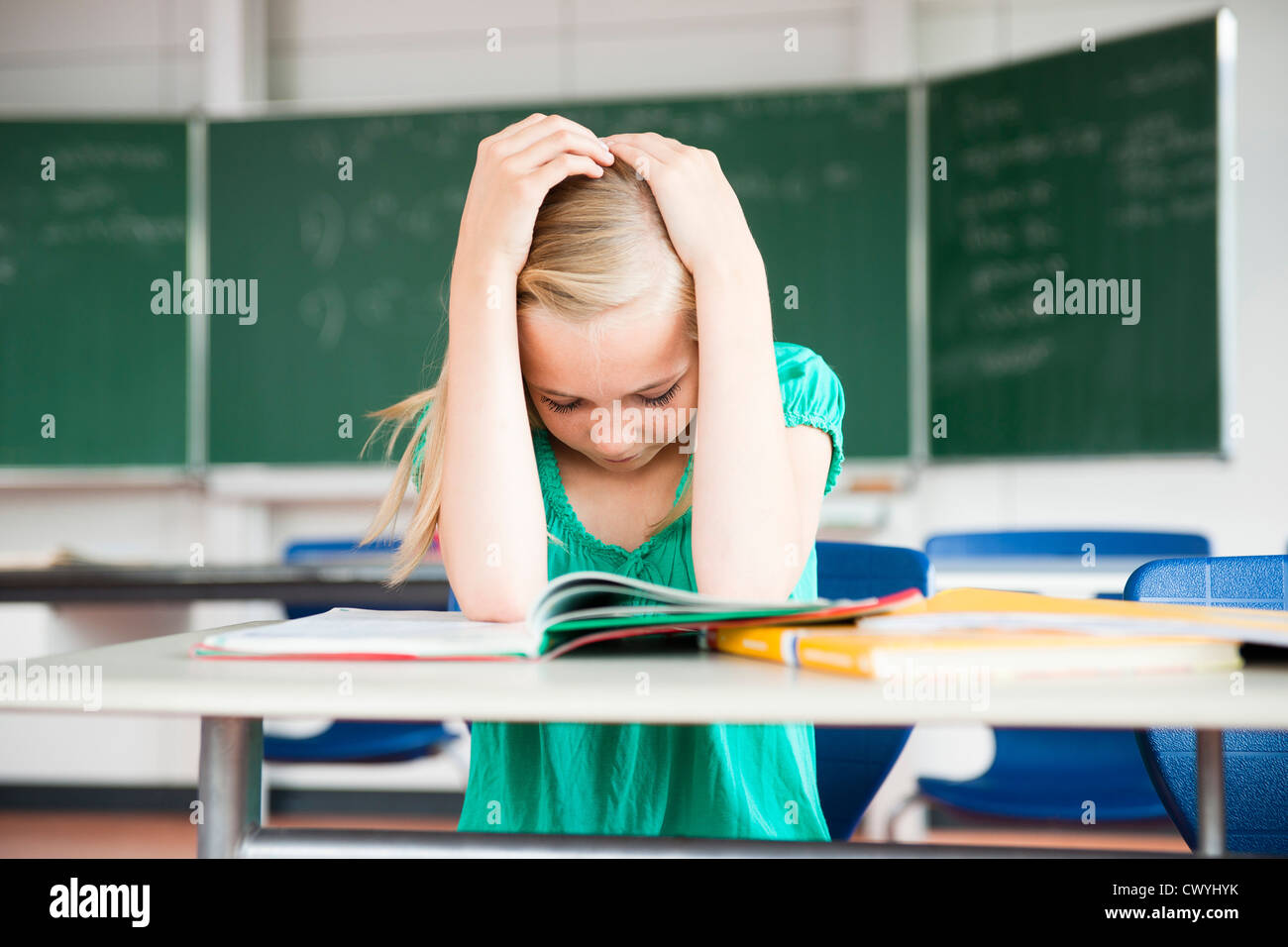 Exhausted teenage girl in classroom Stock Photo