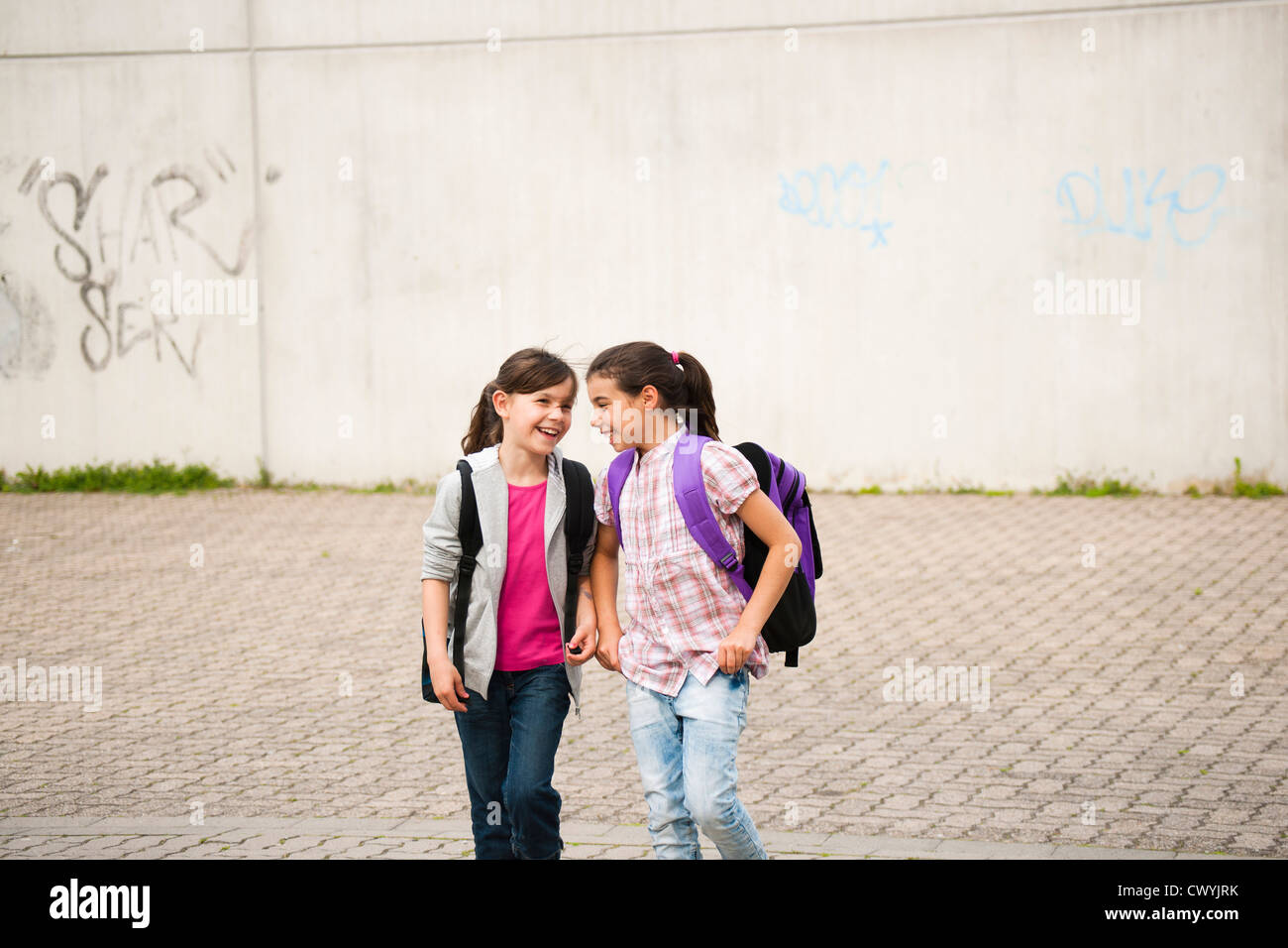 Two smiling girls walking on schoolyard Stock Photo - Alamy