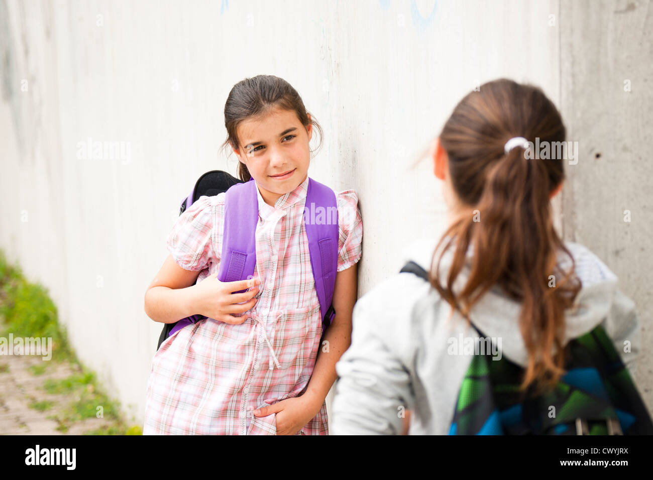 Two girls at concrete wall looking at each other Stock Photo