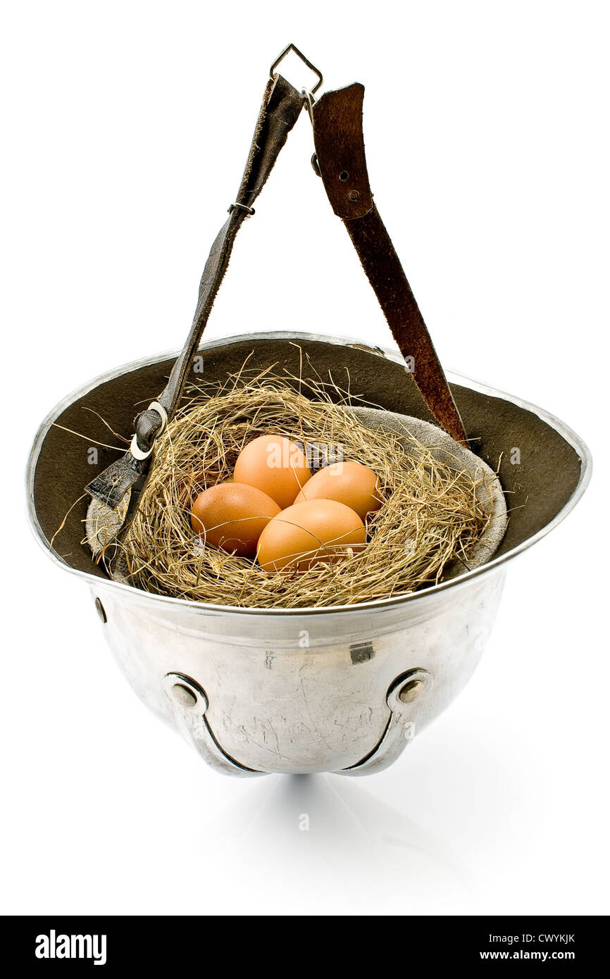 Nest with eggs in old army helmet isolated on white Stock Photo