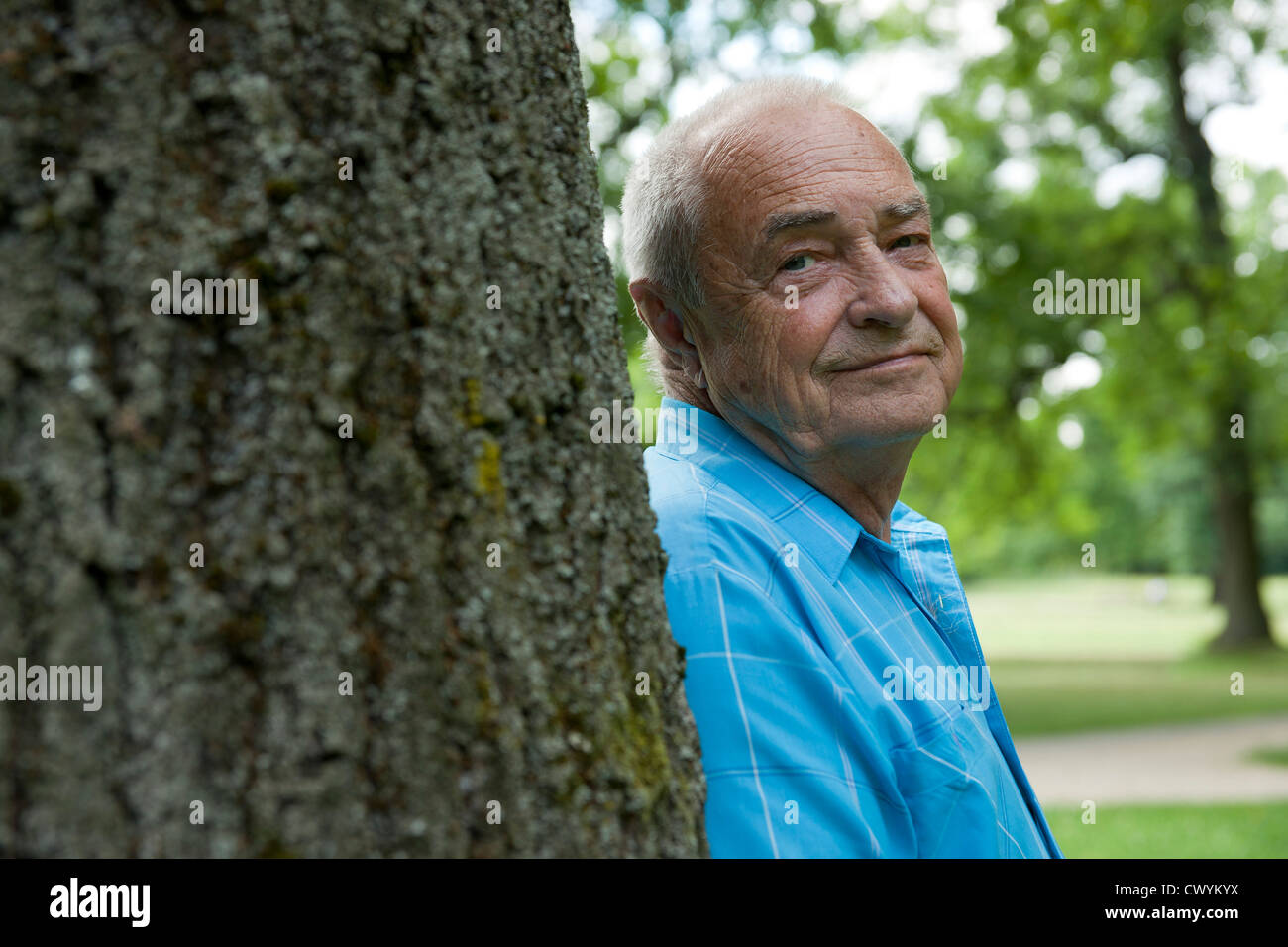 Old man at tree trunk, portrait Stock Photo