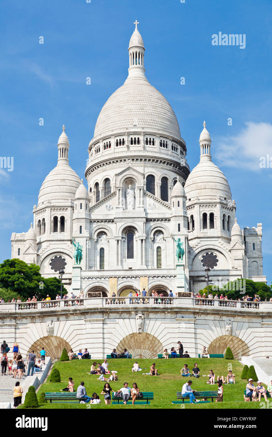Crowds sat on the grass below Sacre Coeur in the Square Louise Michel Paris France EU Europe Stock Photo
