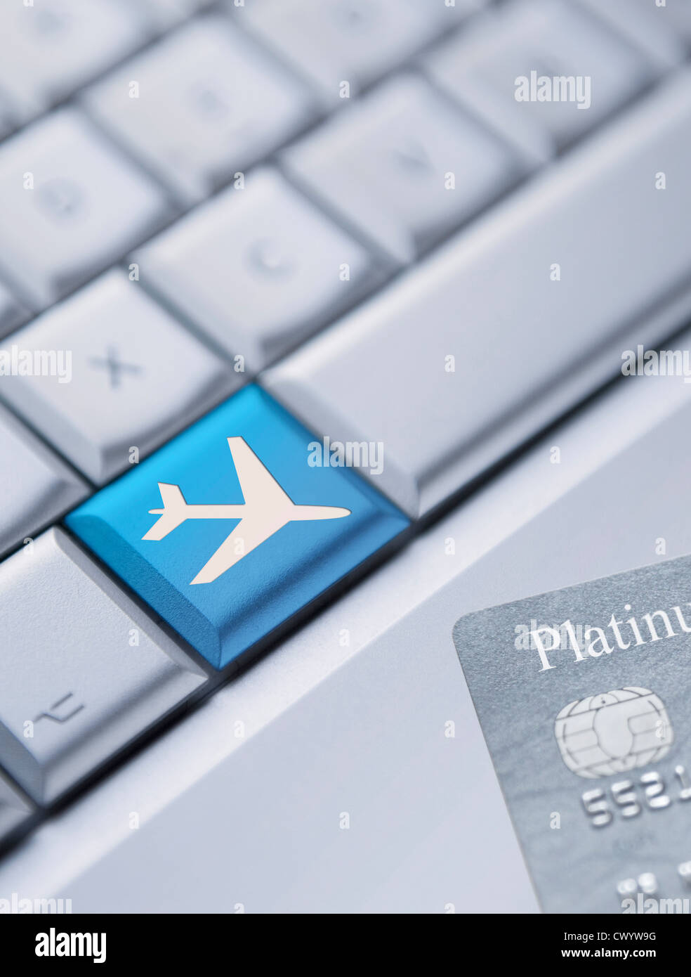 Detail of a laptop keyboard with one blue key with an aeroplane symbol on it and a credit card at the bottom right corner. Stock Photo