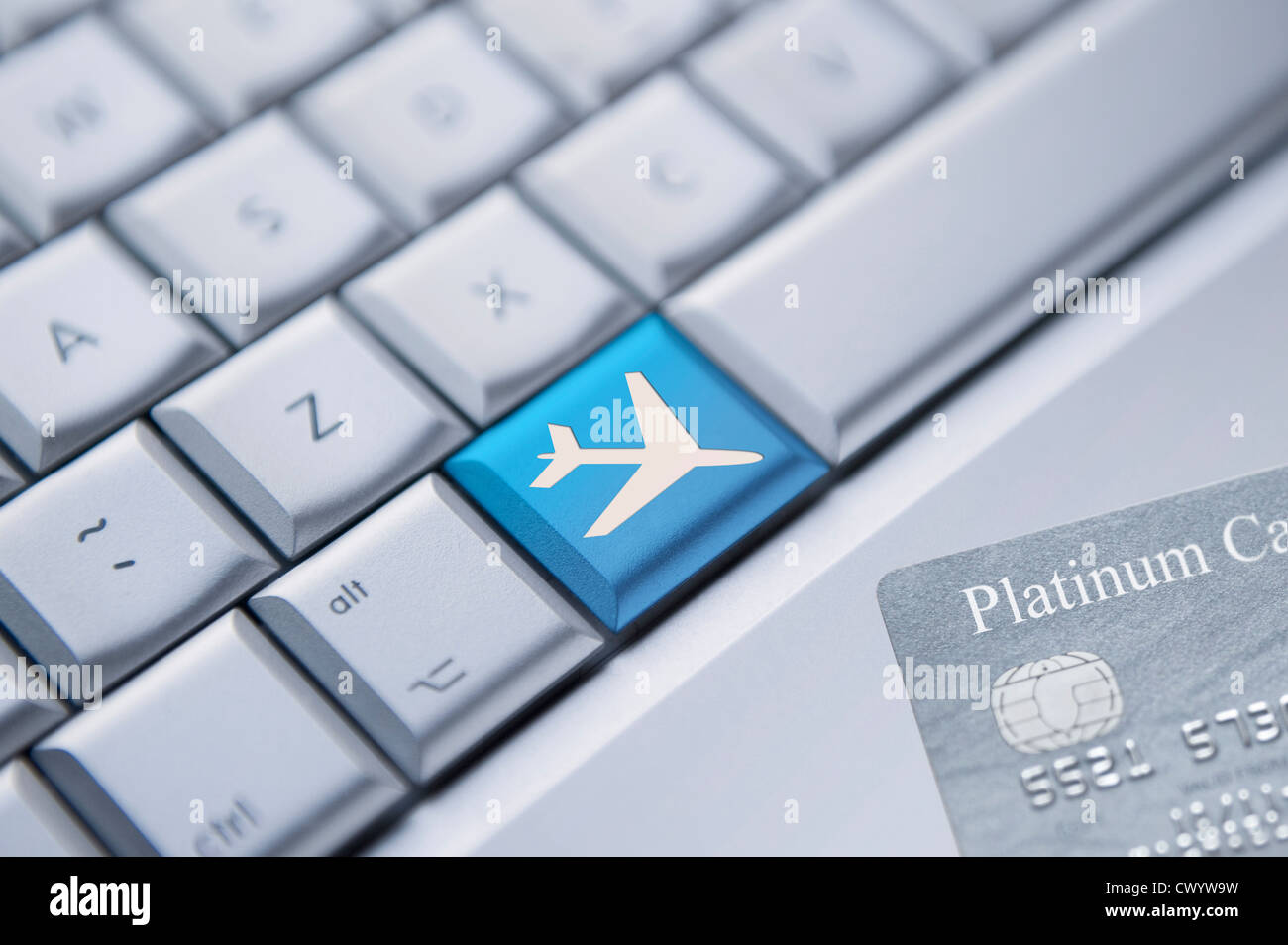Detail of a laptop keyboard with one blue key with an plane symbol on it and a credit card at the bottom right corner. Stock Photo