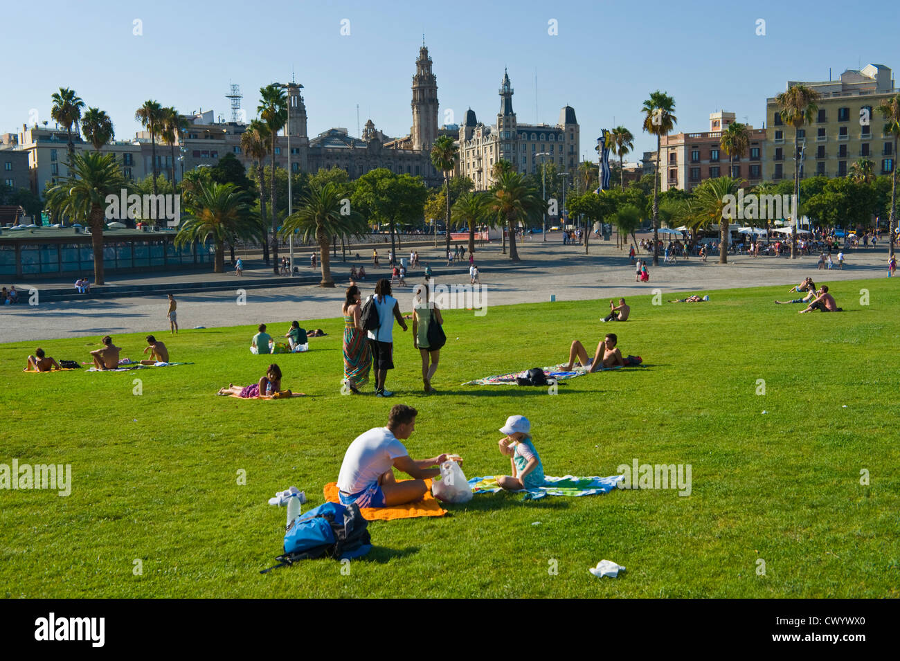 Barcelona people. Lawn with tourists relaxing in the summer sunshine at Port Vell Barcelona Catalonia Spain ES Stock Photo