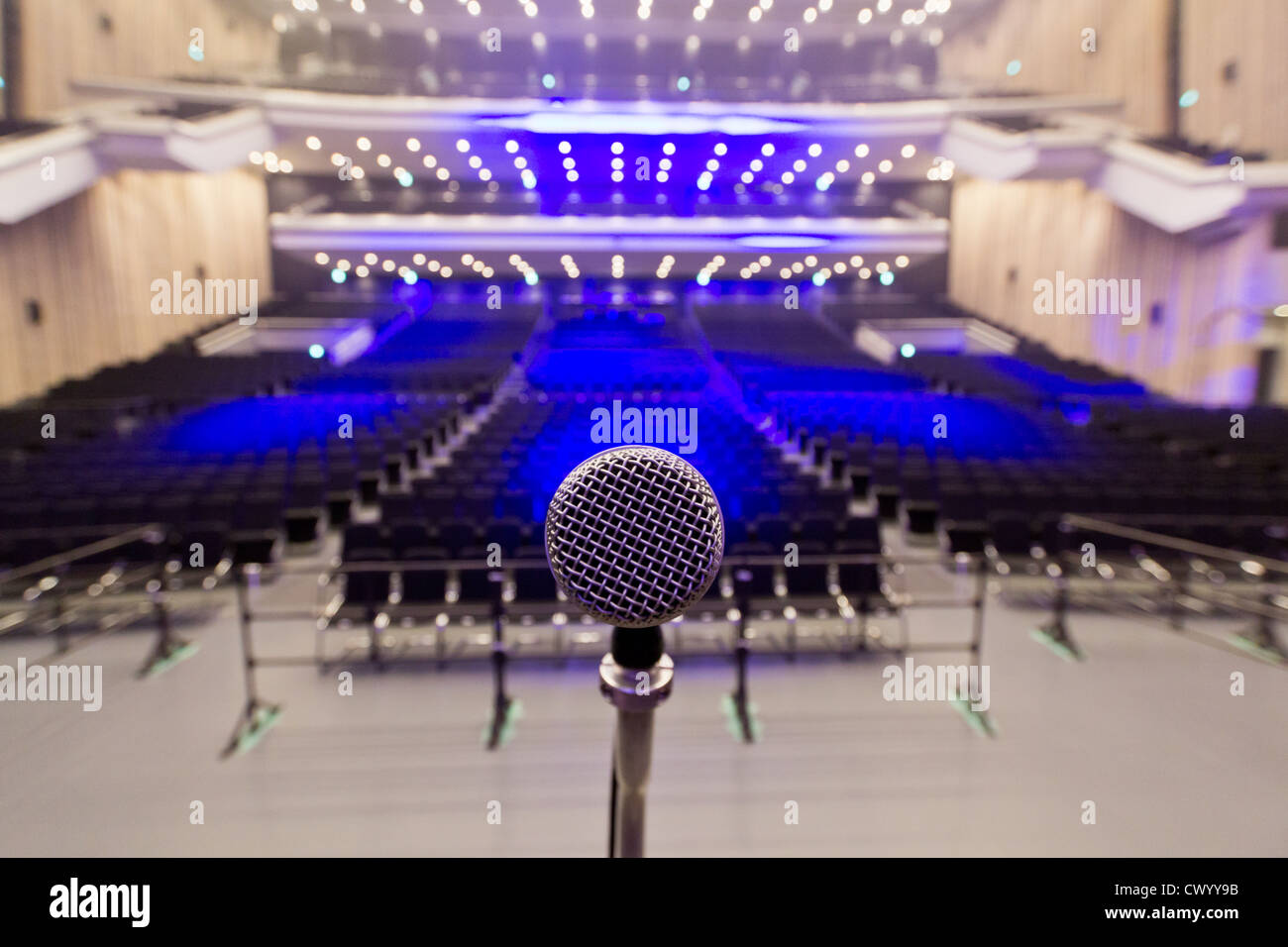 A close-up photo of a microphone in an empty concert venue. Stock Photo