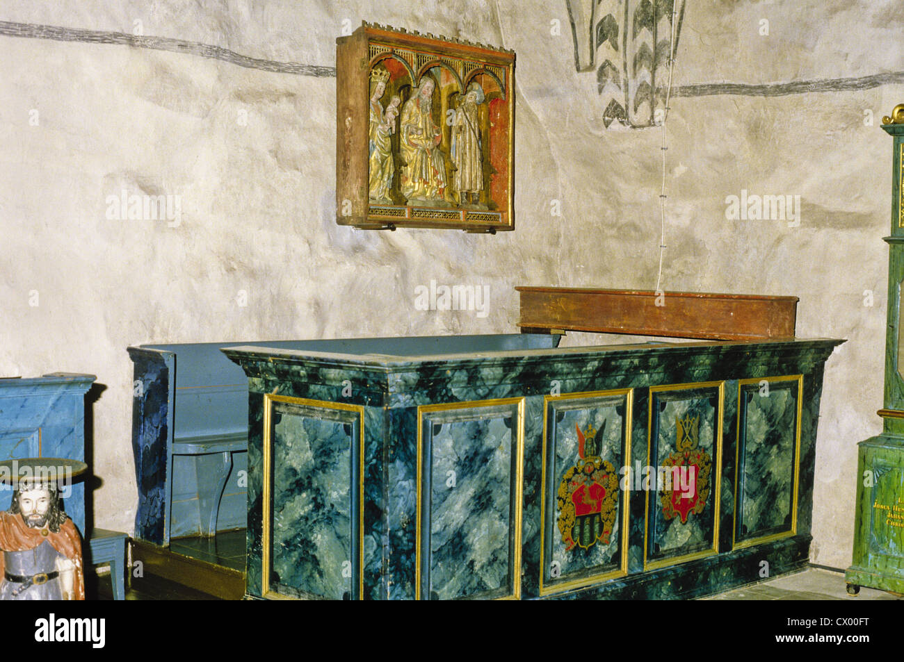 Seating furniture and a triptych with three carved statues in the 15th century church at Rymattyla, Finland Stock Photo