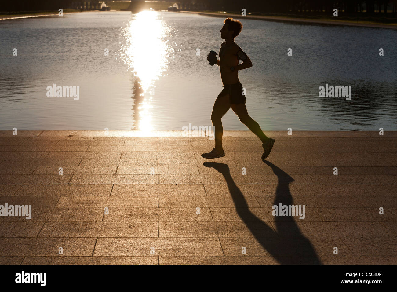 Man running in early morning light reflection - USA Stock Photo