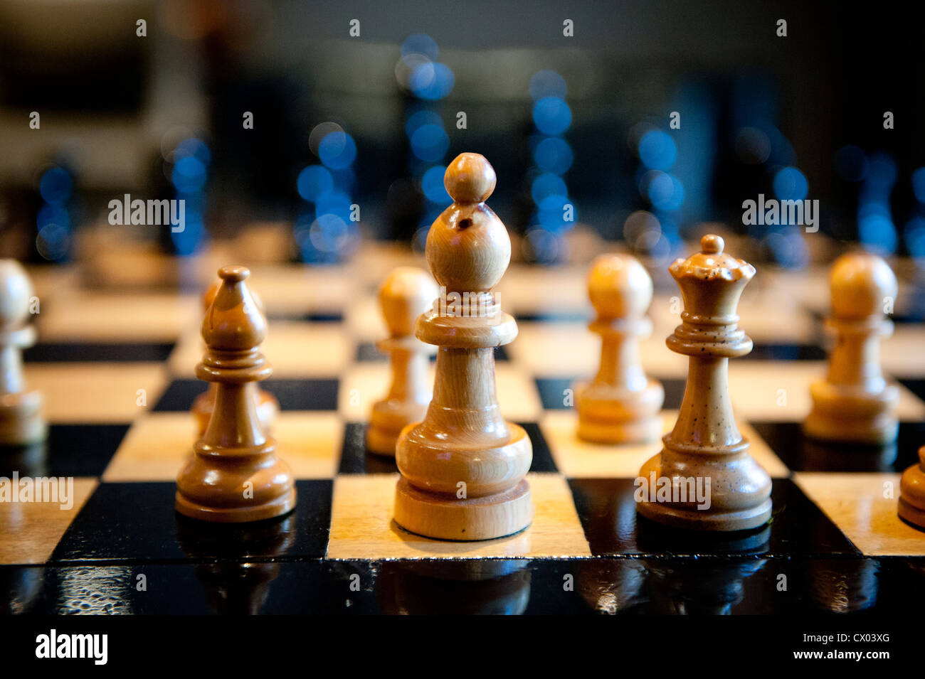 Carved wooden chess pieces on a chess board in warm light. Stock Photo