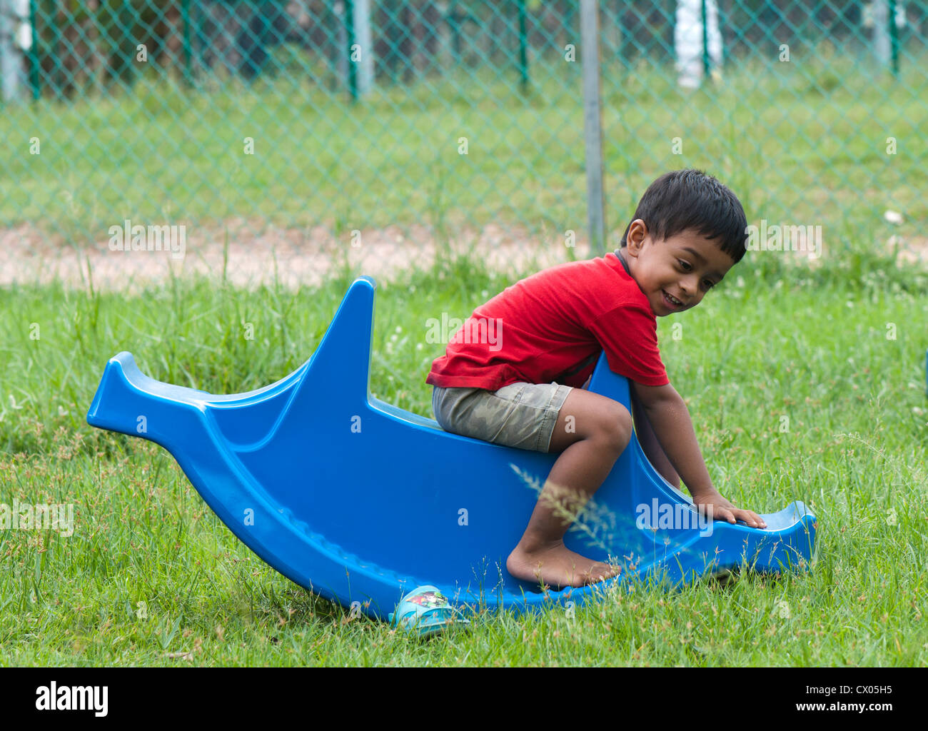 Toddler playing alone in seesaw in a park, India Stock Photo