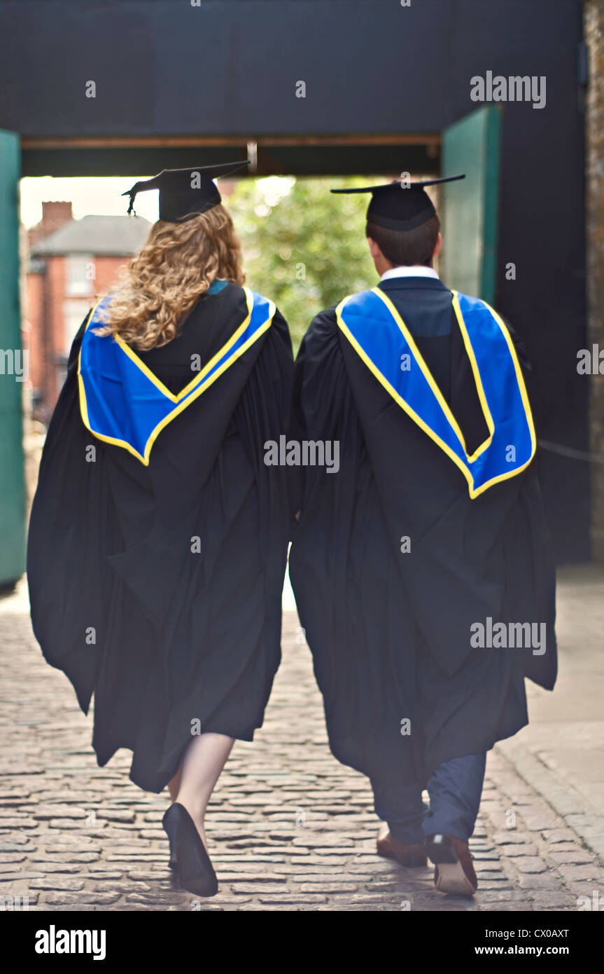 Two graduates walking away together at their graduation ceremony Stock