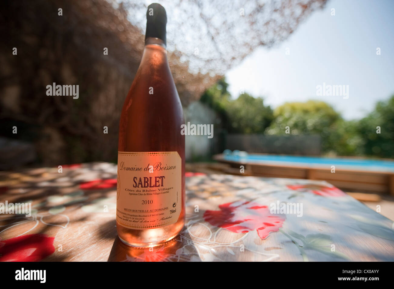 Bottle of chilled Sablet rose wine outdoors by a swimming pool in