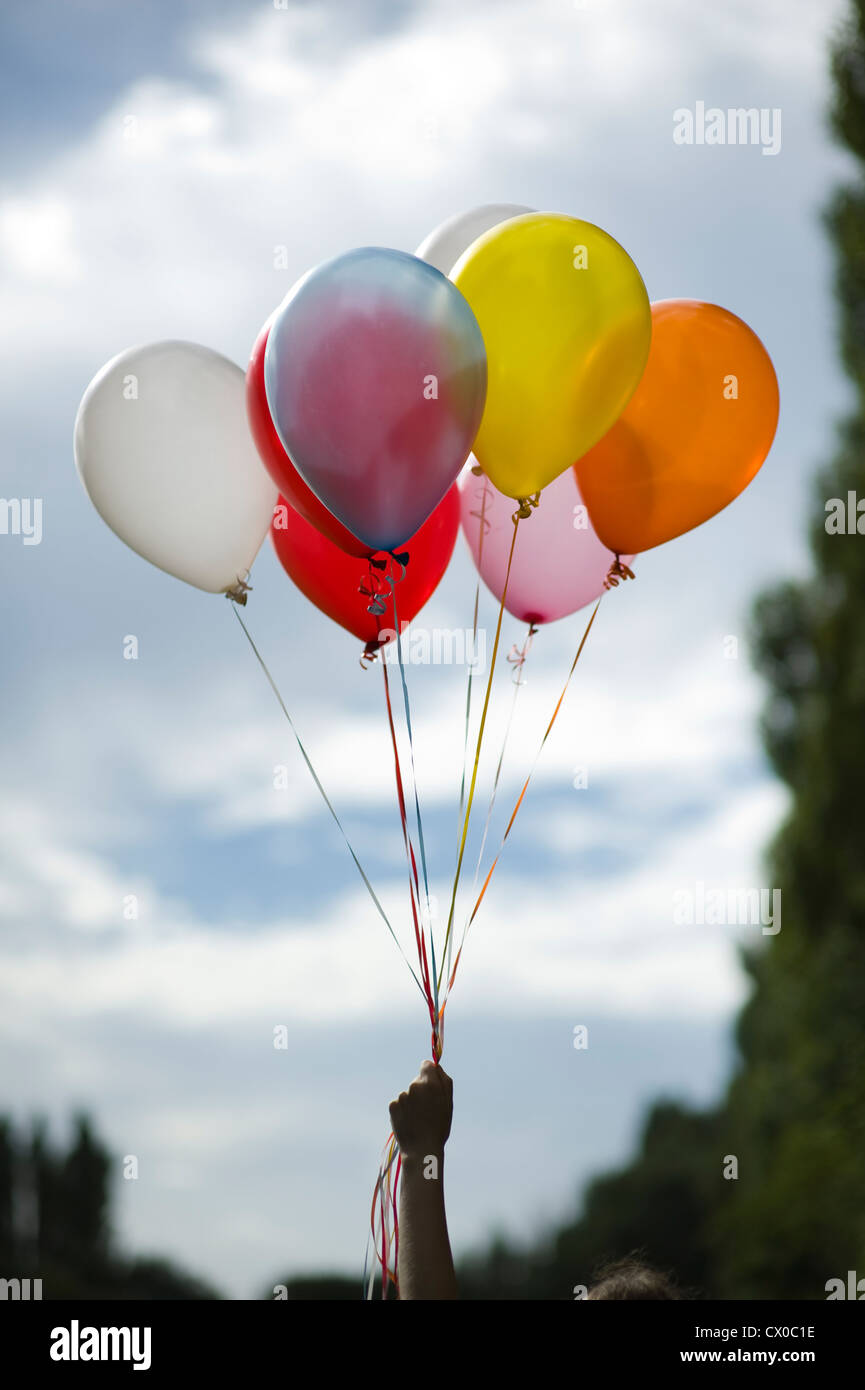 person holding multi colored helium balloons Stock Photo