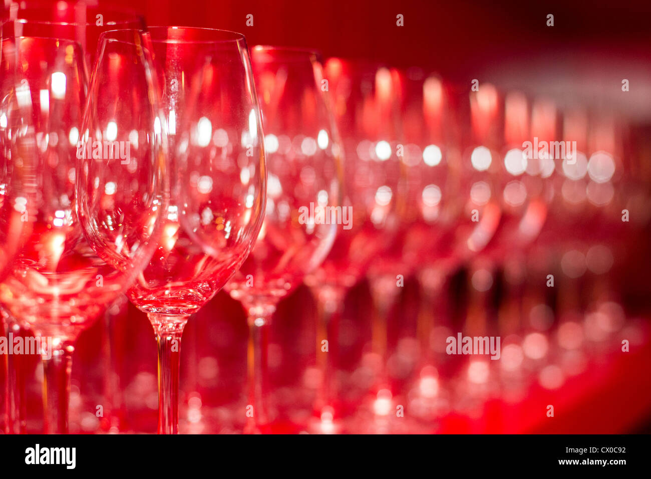 Wine Glasses Lined Up Against a Bright Red Wall Stock Photo