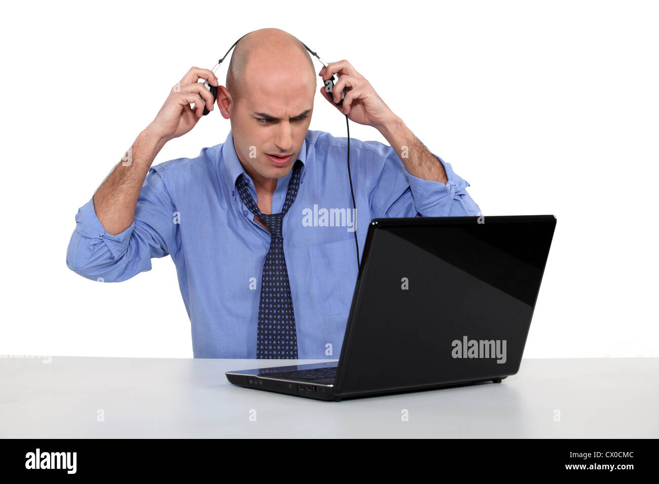 Bald businessman with laptop and headphones Stock Photo