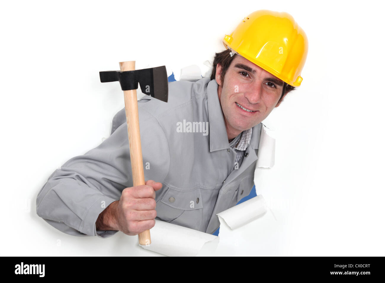 A man popping out a wall in paper with a hatchet. Stock Photo