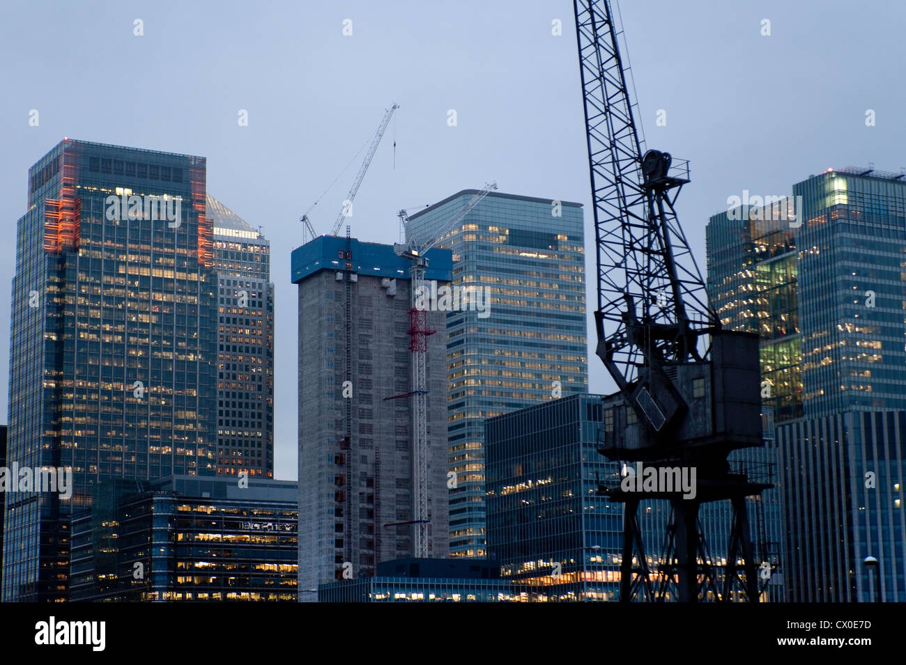 A view at dusk of the City of London skyscrapers with old dockland crane in foreground Stock Photo