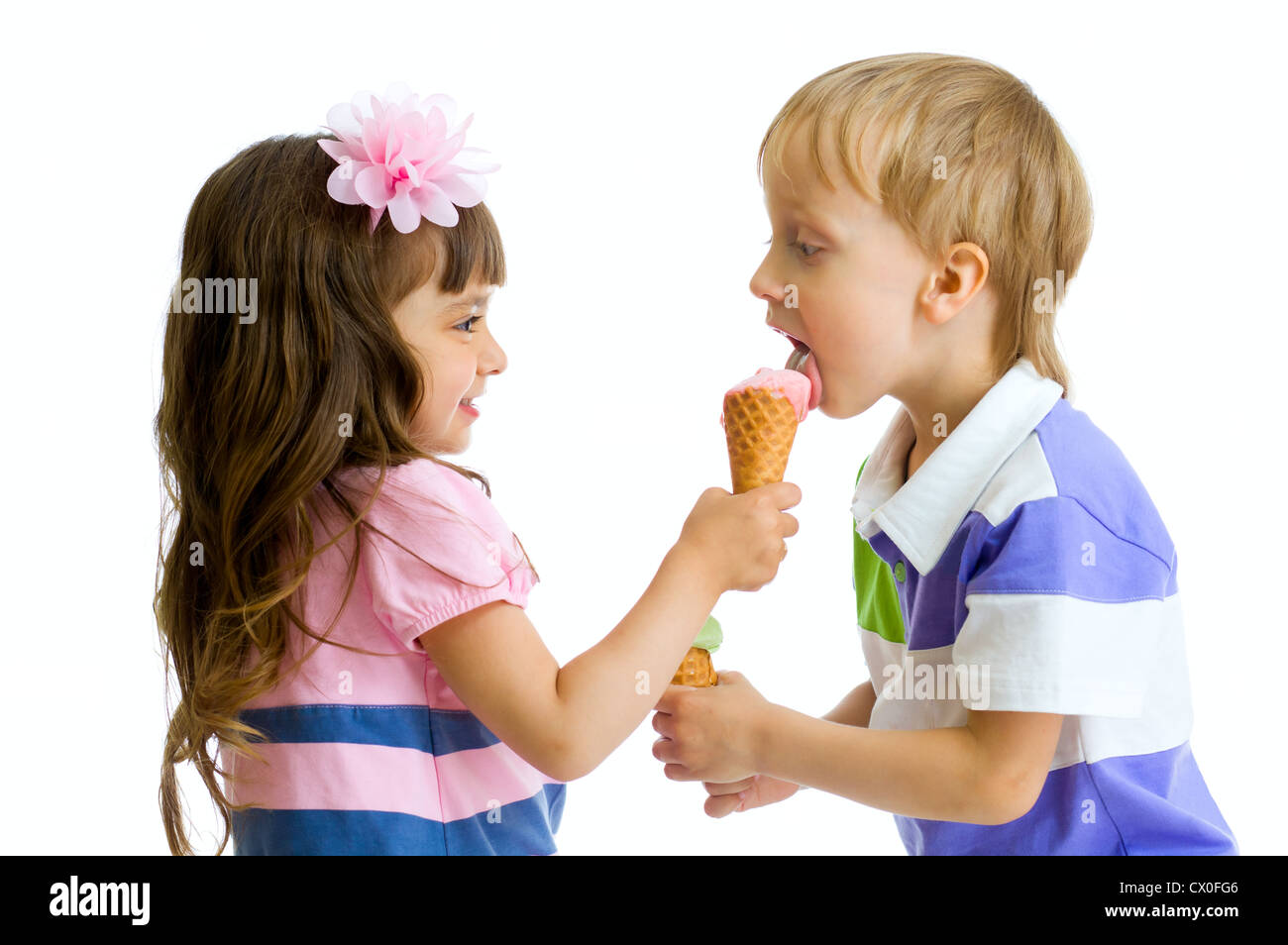 girl shares, gives or feeds boy with her ice cream in studio isolated Stock Photo