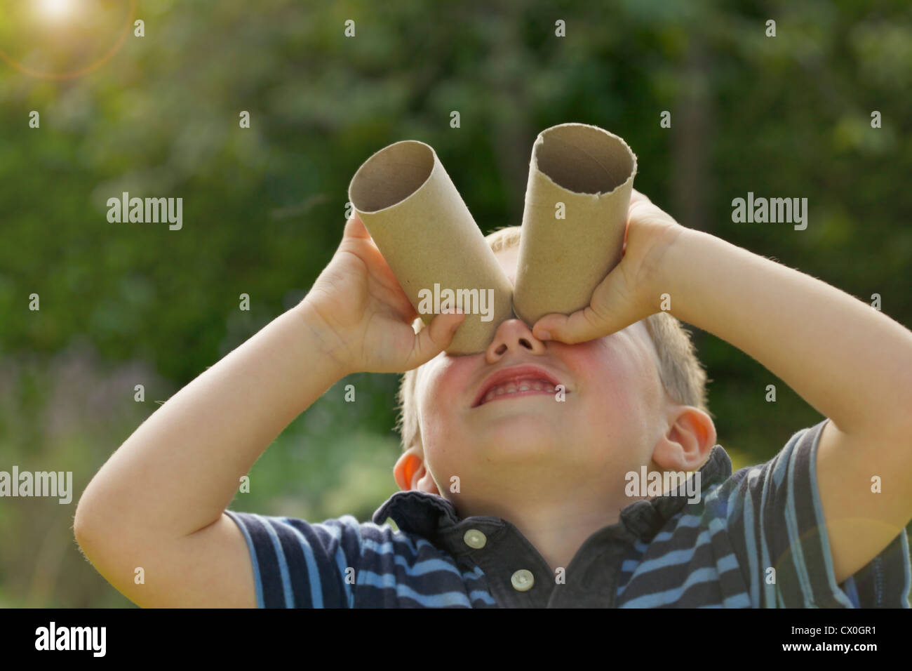 Young Boy Looking Through Empty Toilet Paper Rolls Stock Photo