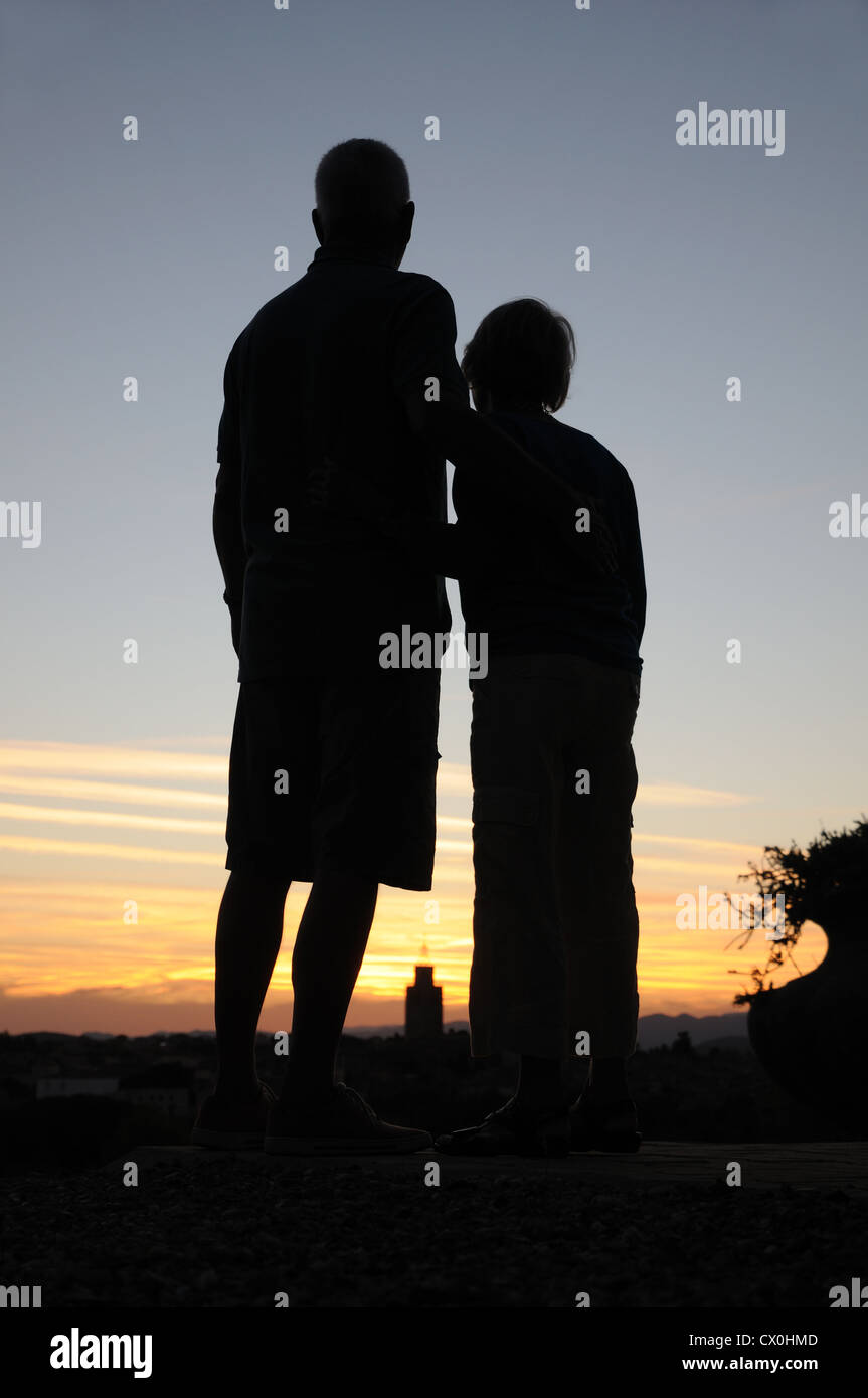 Couple embrace whilst sihouetted against dramatic sunset evening sky in southern France Stock Photo
