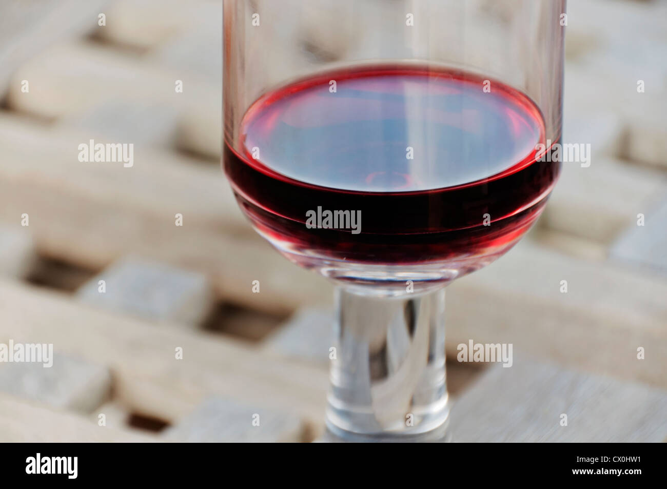 Closeup of a portion of a sturdy plastic wineglass filled  with red wine on an outdoor tabletop. Stock Photo