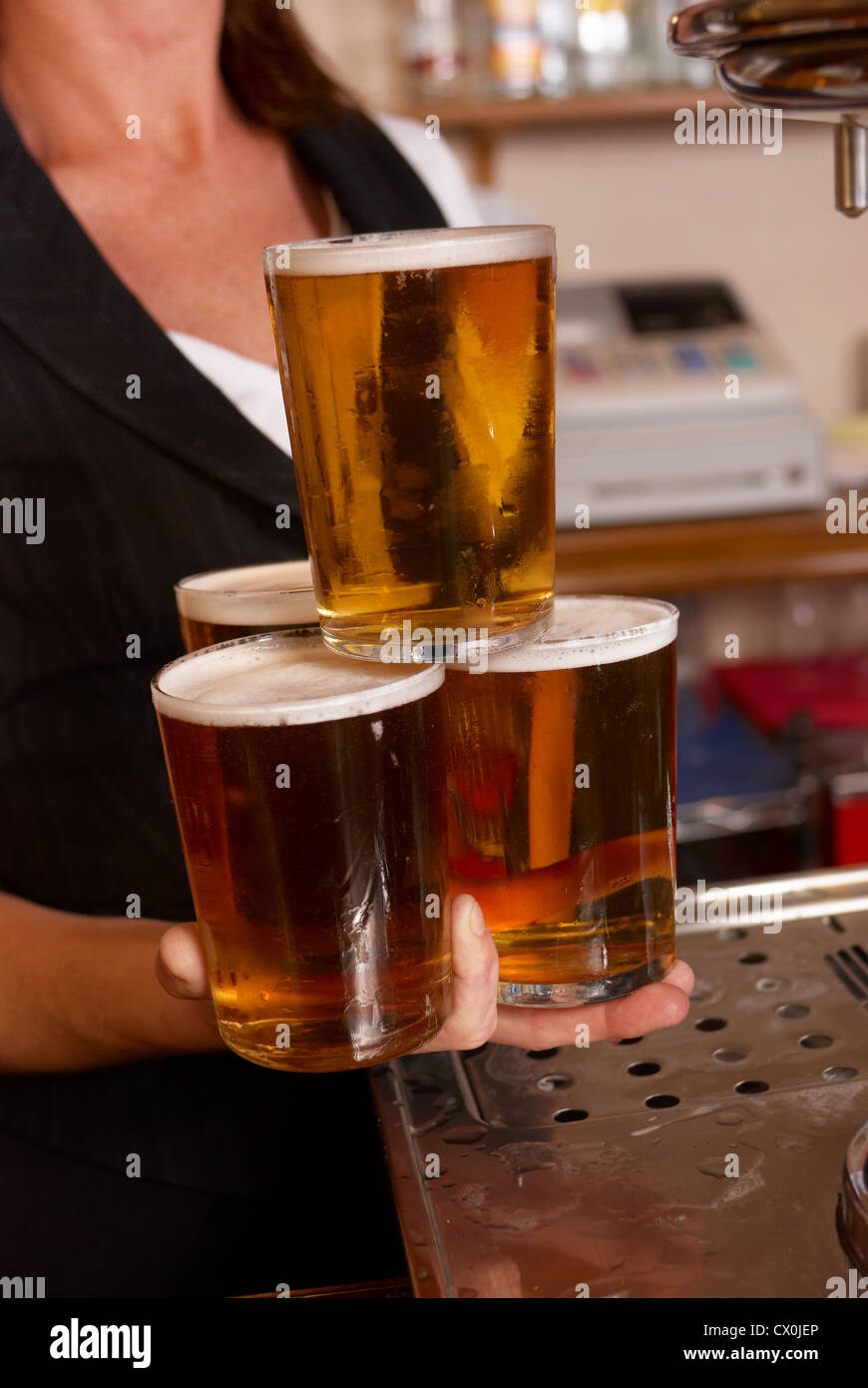 Skilful waitress balancing four full beer glasses Stock Photo