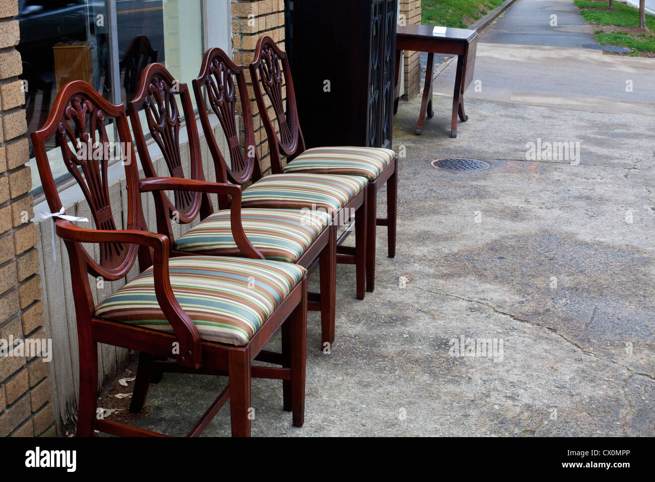 A row of antique chairs for sale on a sidewalk outside an antique shop in Pthe Poncey-Highlands region of Atlanta, Georgia. Stock Photo