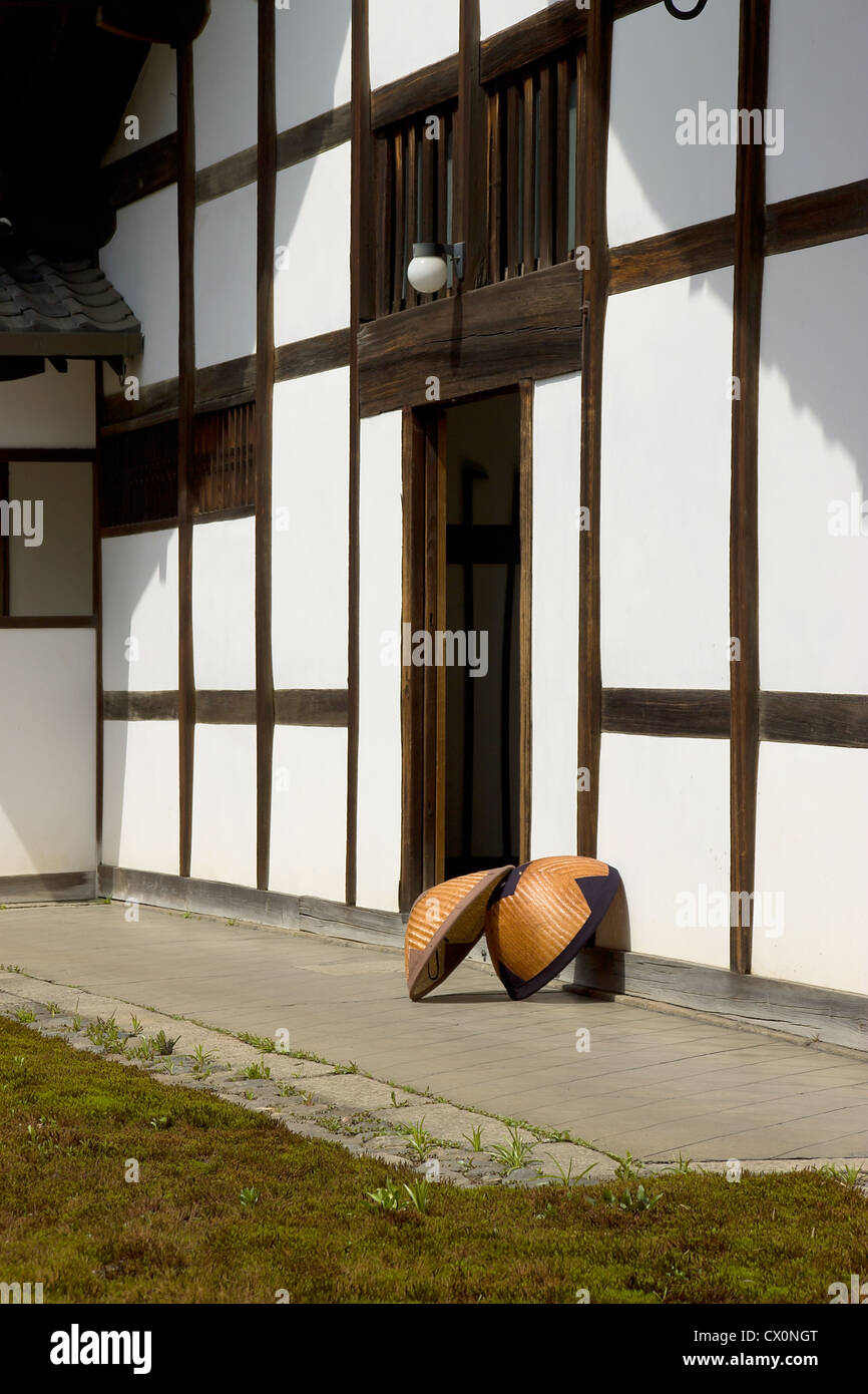 Two traditional Japanese straw rain hats (amegasa) in the yard of