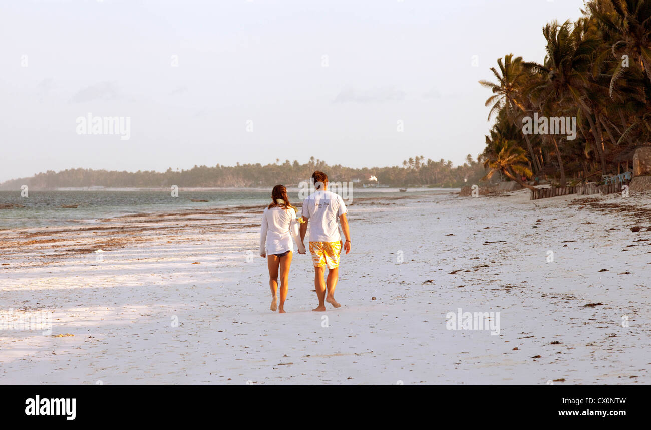 Zanzibar Beach; Young couple walking holding hands on the beach, Bwejuu, Zanzibar Africa; example of Africa travel Stock Photo