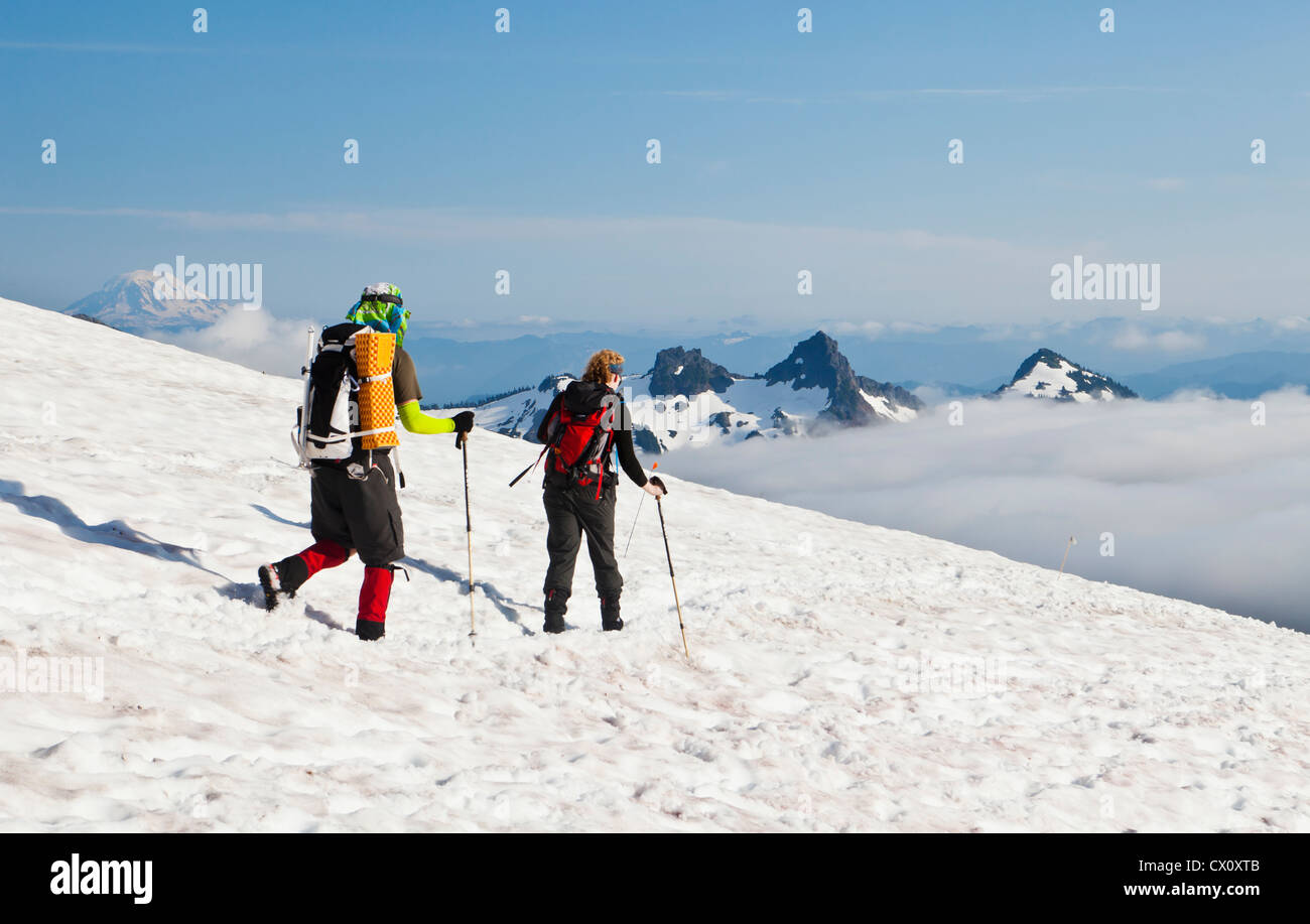 Climbers descending Mount Rainier with Mount Adams and the Tatoosh range in the background. Washington, USA. Stock Photo