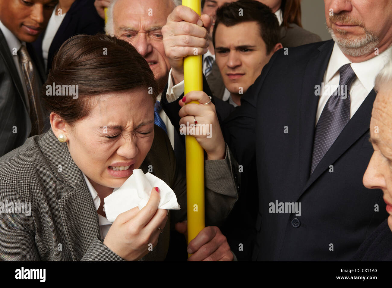 Businesswoman sneezing on subway train Stock Photo