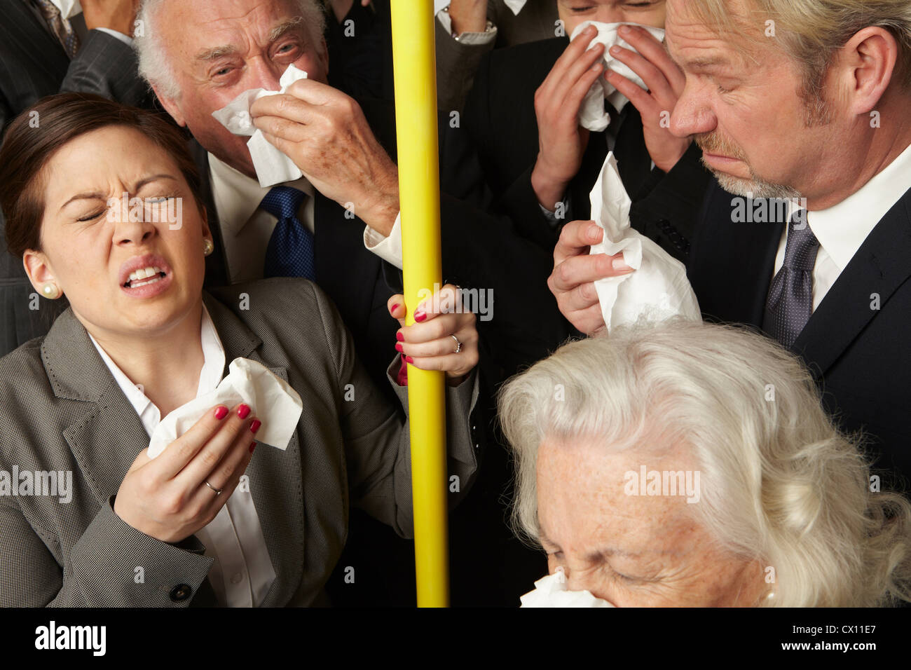 Businesspeople sneezing on subway train Stock Photo