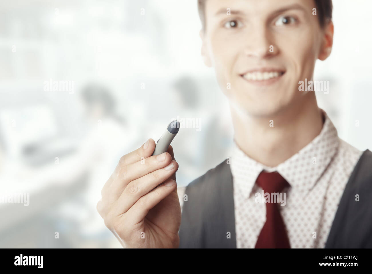 Smiling businessman holding a pen at his office Stock Photo - Alamy