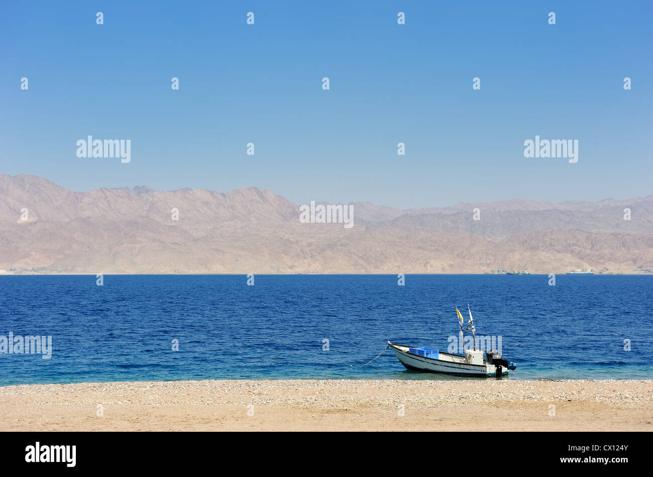 Gulf of Eilat Red Sea, the boat on the shore and Jordanian mountains in the background. Stock Photo