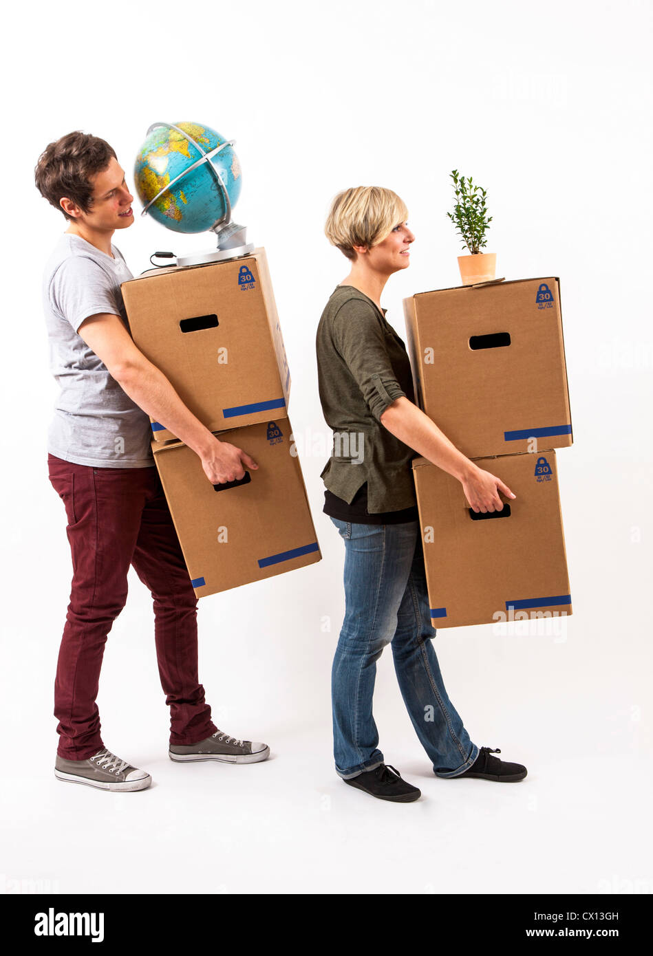 Symbolfoto Umzug, Auszug, umziehen. Junges Paar trägt Umzugskartons, Zimmerpflanze und Globus. Umzugskisten aus Pappkarton. Stock Photo