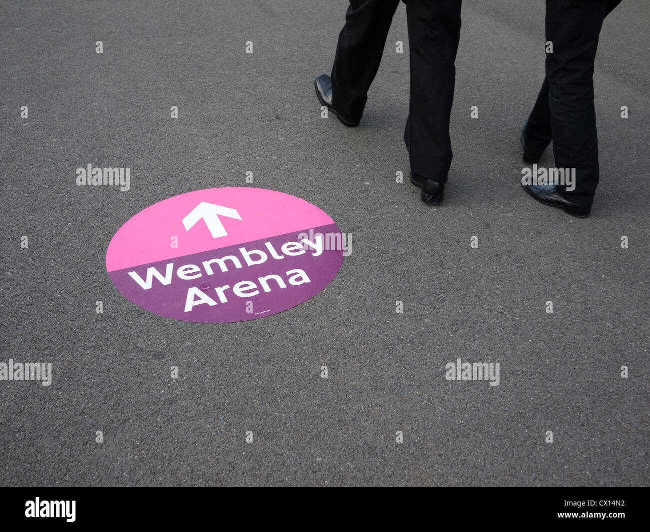 Direction sign to Wembley arena at Wembley Stadium London UK with people walking by Stock Photo