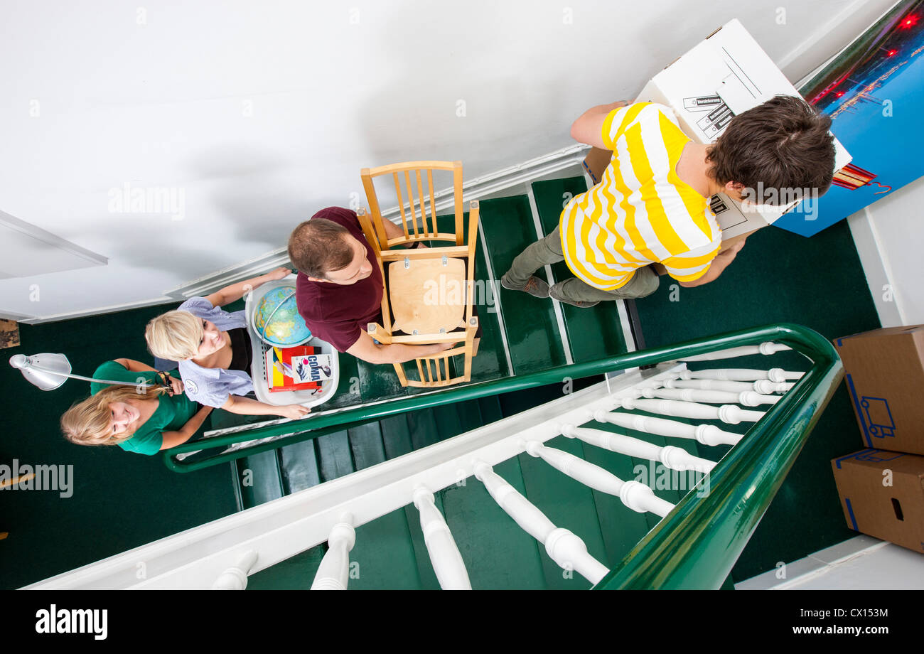 Young people moving in to a new apartment. Friends help carrying moving ...