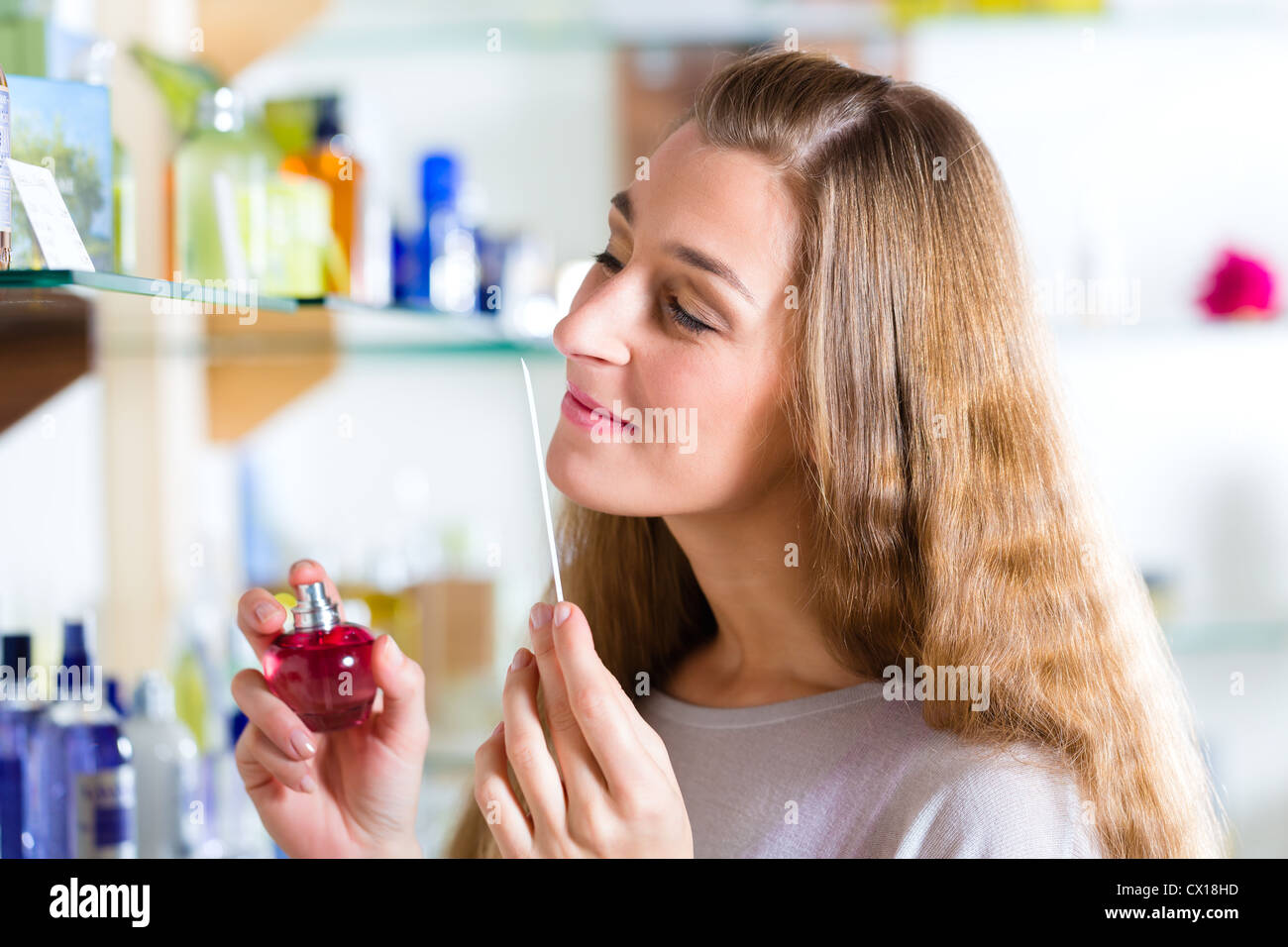 Young woman buying perfume in a shop or store, testing the fragrance