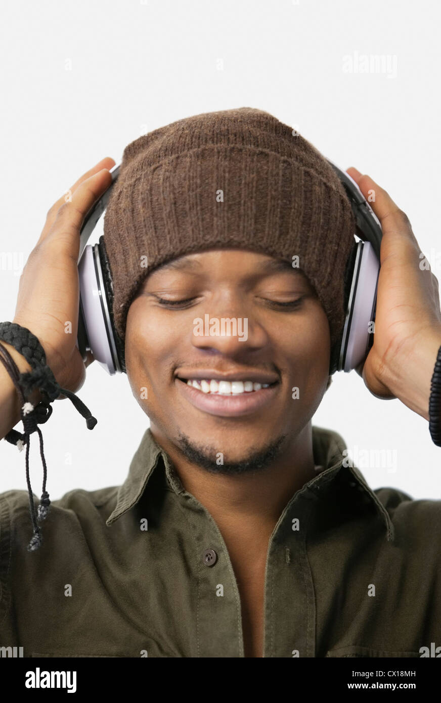 Closeup of relaxed young man listening music through headphones Stock