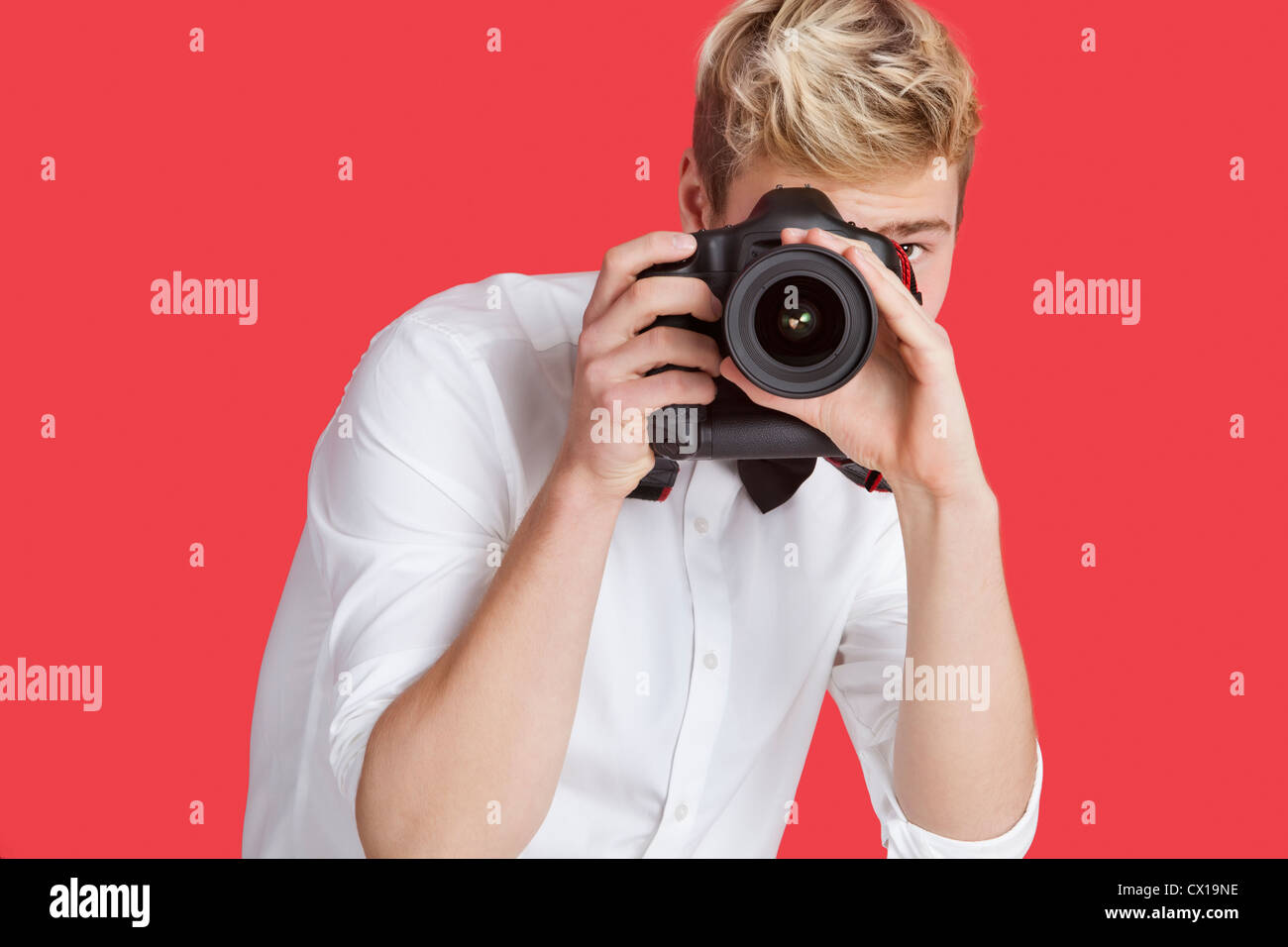 Young man taking picture with digital camera over red background Stock Photo