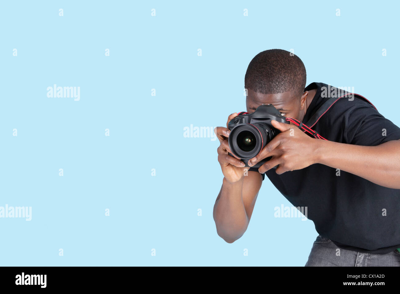 Young man taking photo through digital camera over blue background Stock Photo