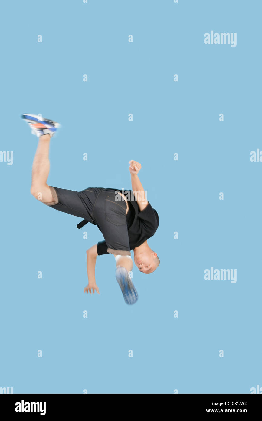 Teenage boy break dancing over blue background Stock Photo