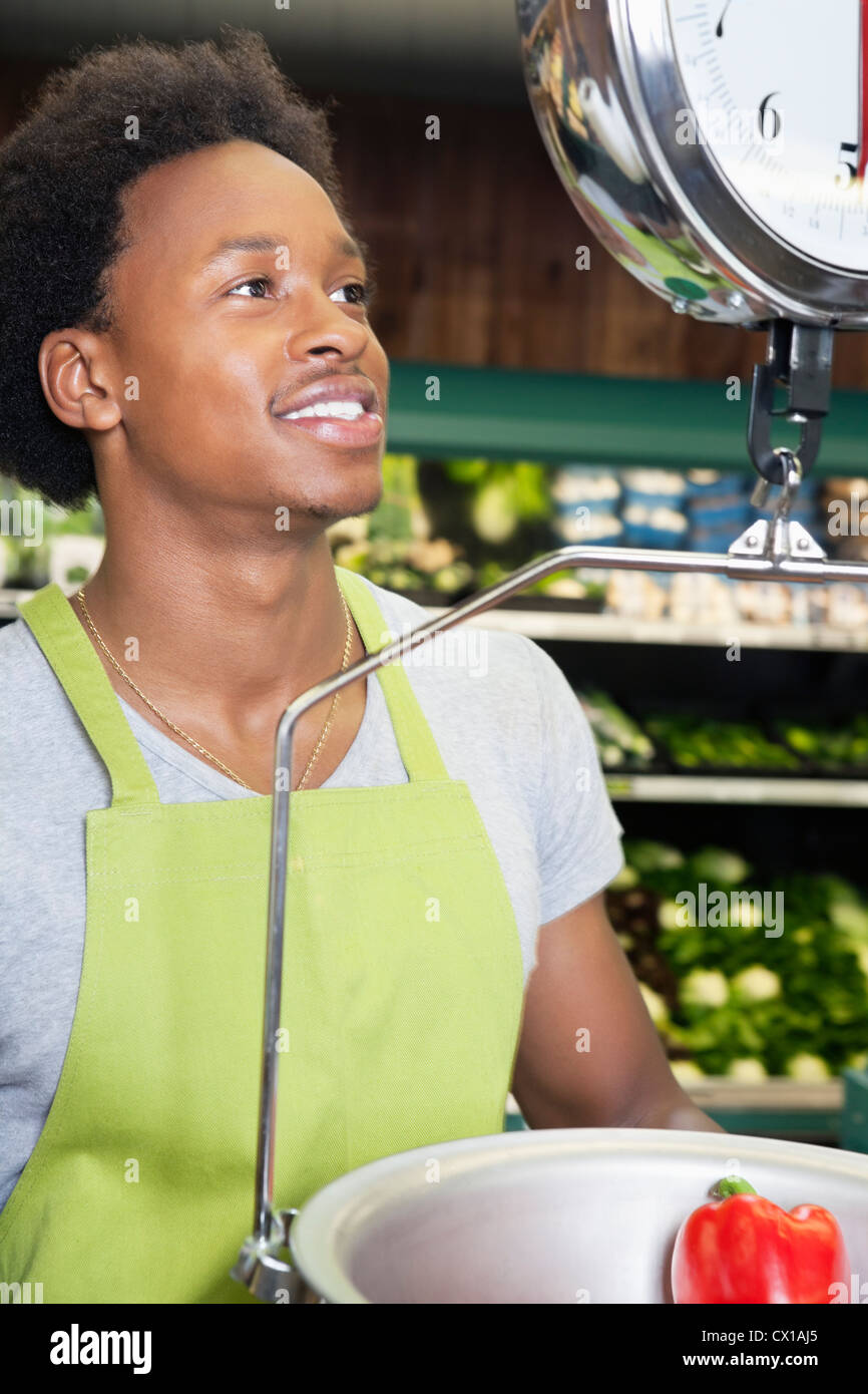 African American male store clerk weighing bell pepper Stock Photo